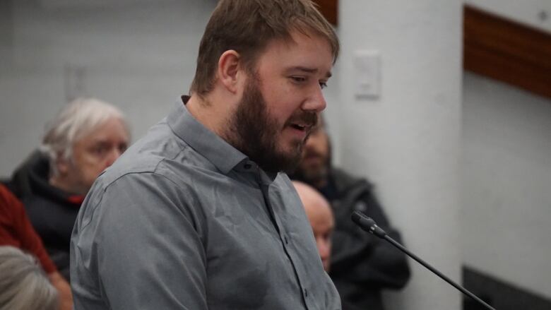 A man speaks at a microphone podium.