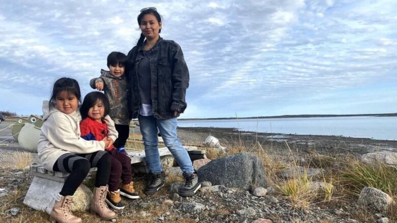 A woman and her three children face the camera.