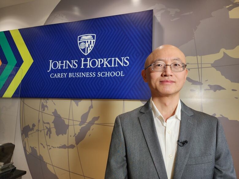 A well dressed man standing in front of a sign reading 