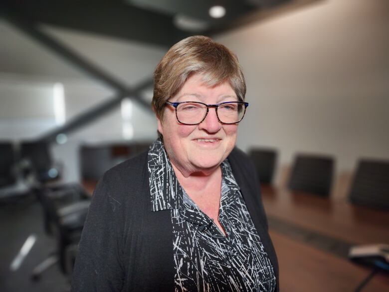 A woman smiles at the camera in a boardroom.