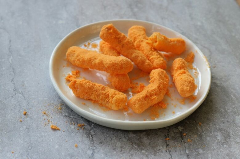 Orange Cheezies sit on a plate in a kitchen.