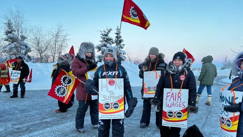 People in winter clothing carrying signs. 