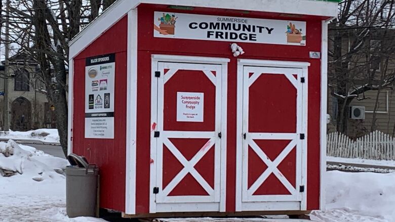 A small red shed with white doors and a sign reading 