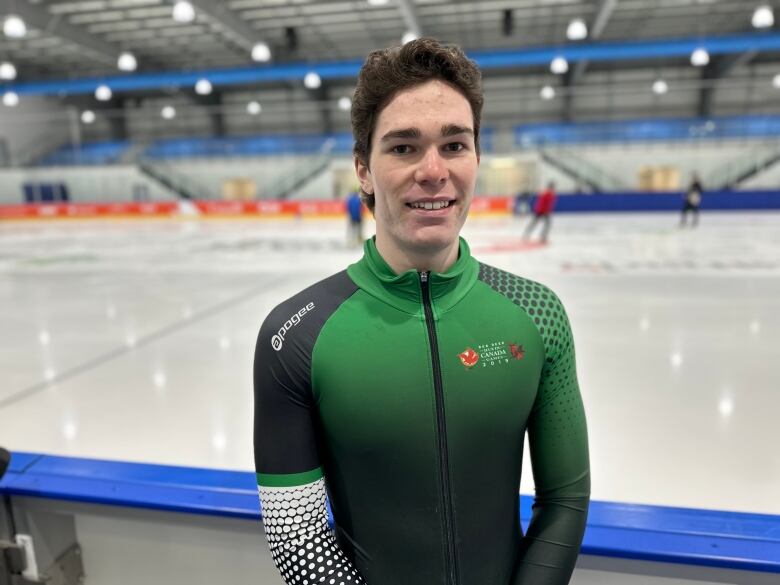 A speed skater in a Team PEI uniform stands next to an ice surface. 