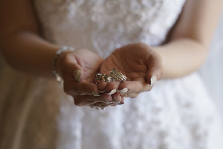 A hand holding wedding bands.