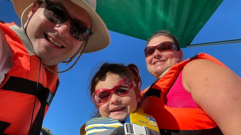 a family takes a selfie - they are all smiling and wearing life jackets 