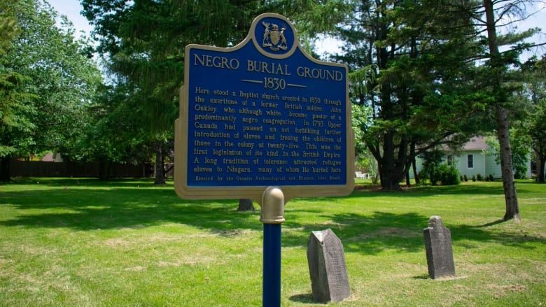 A sign in front of two headstones.