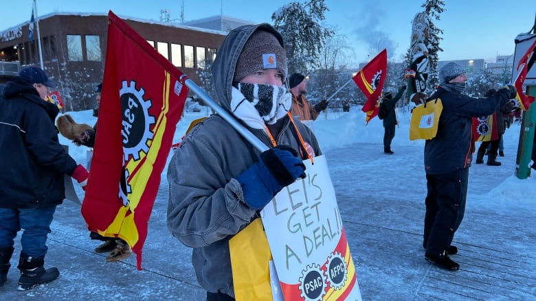 Bundled up person with yellow sign.