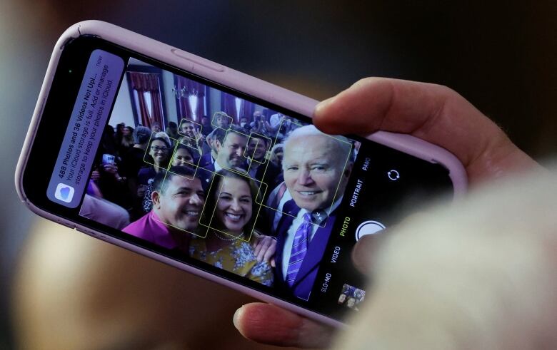 U.S. President Joe Biden holds a phone, in order to take part in a selfie captured at an event in Tampa, Fla.