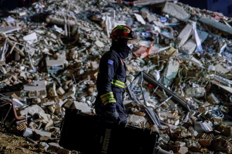 A member of a rescue team stands in front of a collapsed building in Turkey.