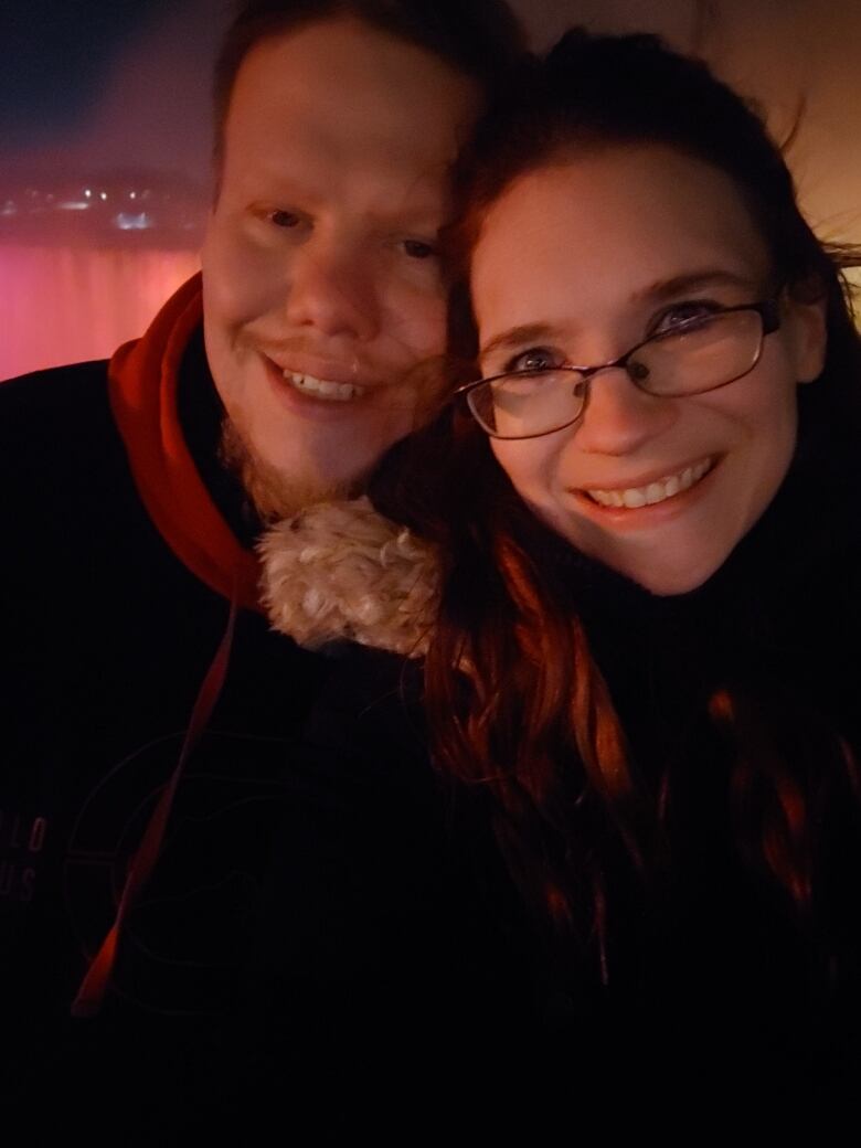 Sean Parsons and Charlene Allen pose in front of the Niagara Falls at night.