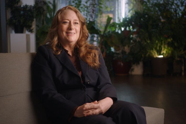 Smiling, red-haired woman sits on a cream coloured chair