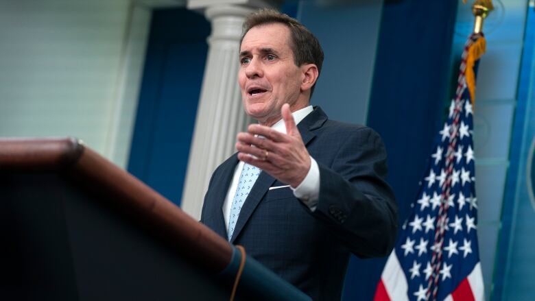 A person gestures while speaking at a lectern.