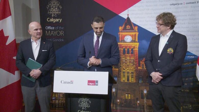 Three men stand behind a podium.