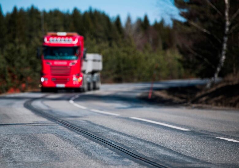 A wide shot of a truck driving on a highway.