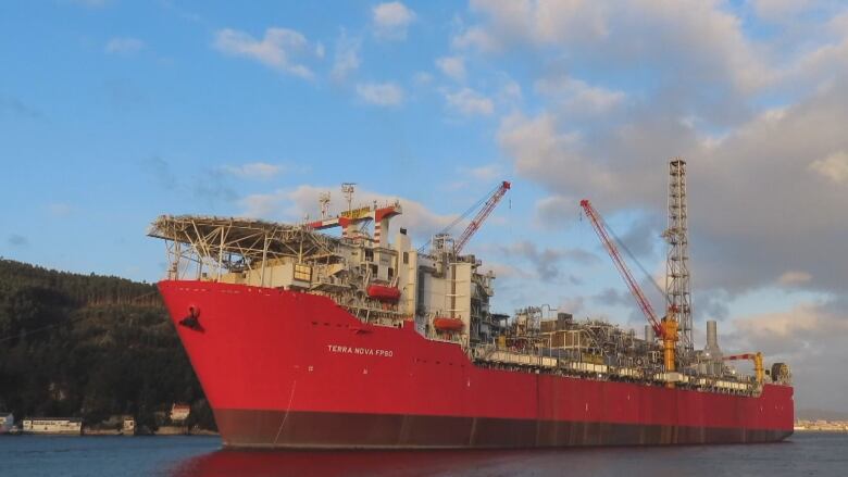 A large red ship with industrial equipment on deck.