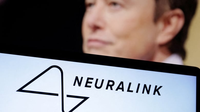 The Neuralink logo is seen in the foreground, in front of a man's face which is blurry. 