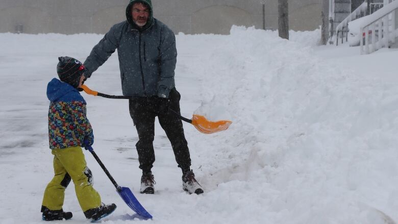 A father and son shovel out after a heavy snowfall.