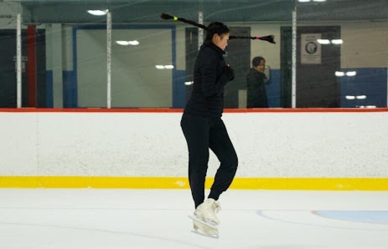 A figure skater dressed in black jumps in the air 