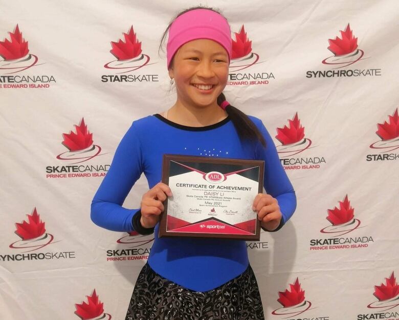 A young figure skater holds a certificate of achievement. 