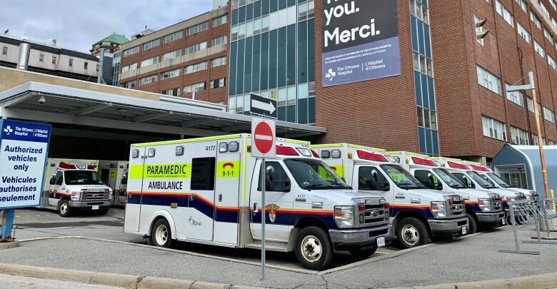 More than a half dozen ambulances parked outside the emergency department of a hospital.