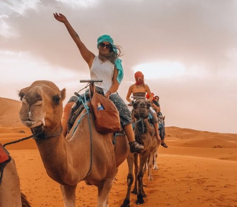 Allison Lang sits on the back of a camel in the desert.