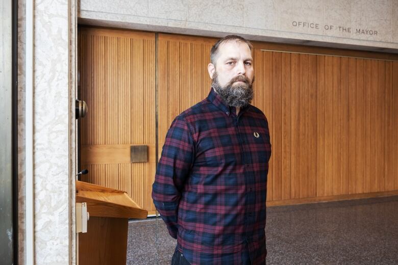 A man in blue-and-red plaid standing in the foyer at city hall.