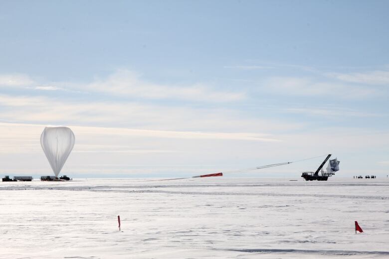 A large white balloon is inflated on a runway.