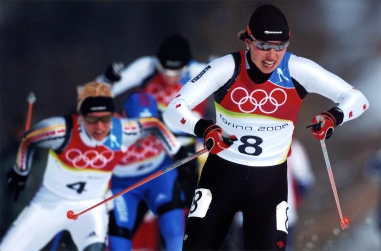 A woman skis ahead of competitors with a look of determination on her face.