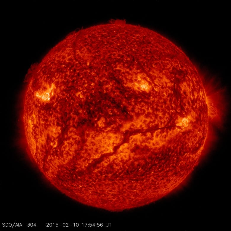 A satellite photo shows the sun, with a darker line stretching from roughly the 7 o'clock position and winding up towards the 3 o'clock position. 