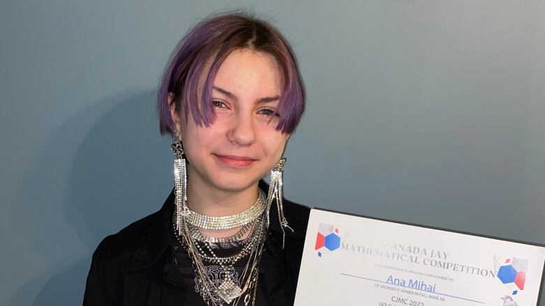 A young girl is seen smiling, holding a certificate.