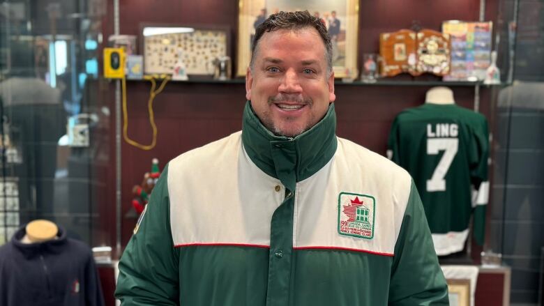 A man wears a green and white 1991 volunteer jacket 