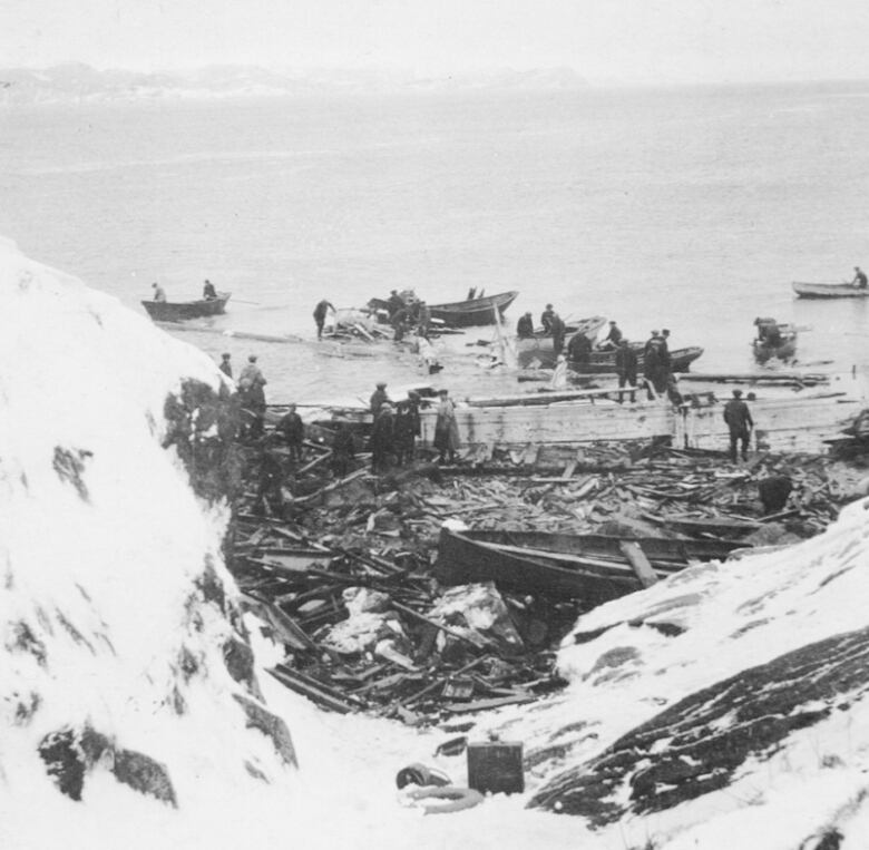 Men are pictured among a ship's wreckage on an island coastline.