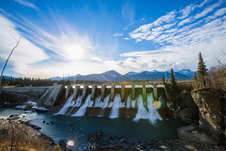 A dam in Kananaskis Alta. runs with the Rocky Mountains in the background.