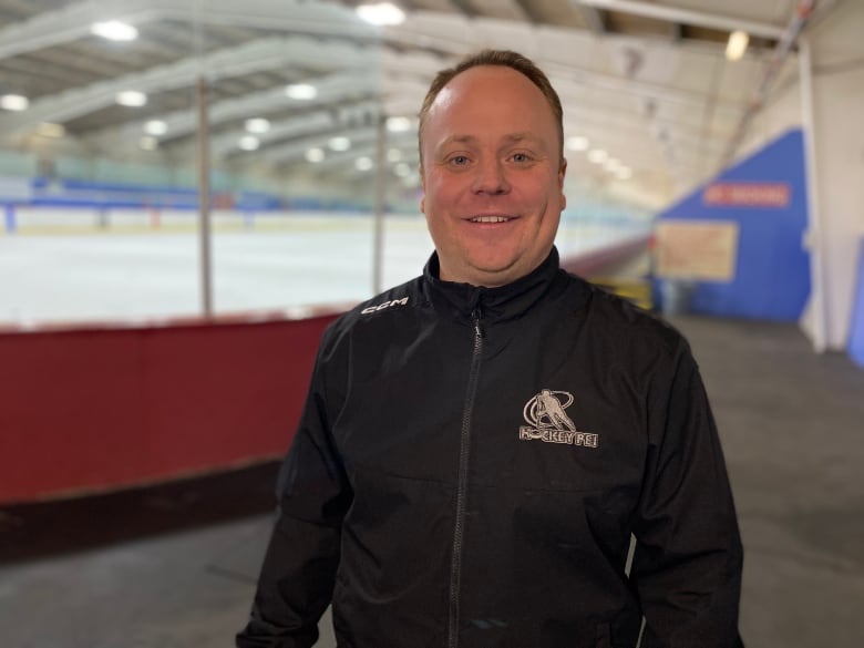 A hockey coach stands in a rink 