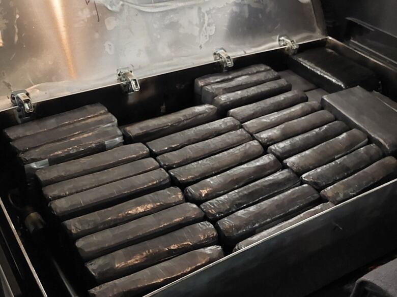 More than two dozen bricks of cocaine in an open metal box.