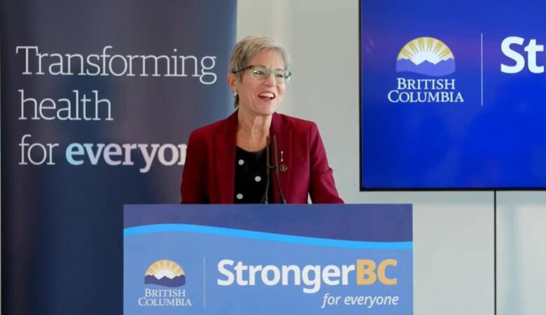 A woman stands behind a podium.