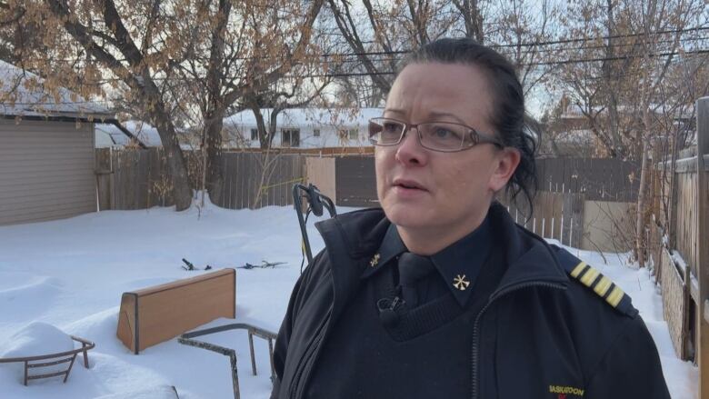 A woman clad in a fire chief's apparel standing in a snow covered lot.