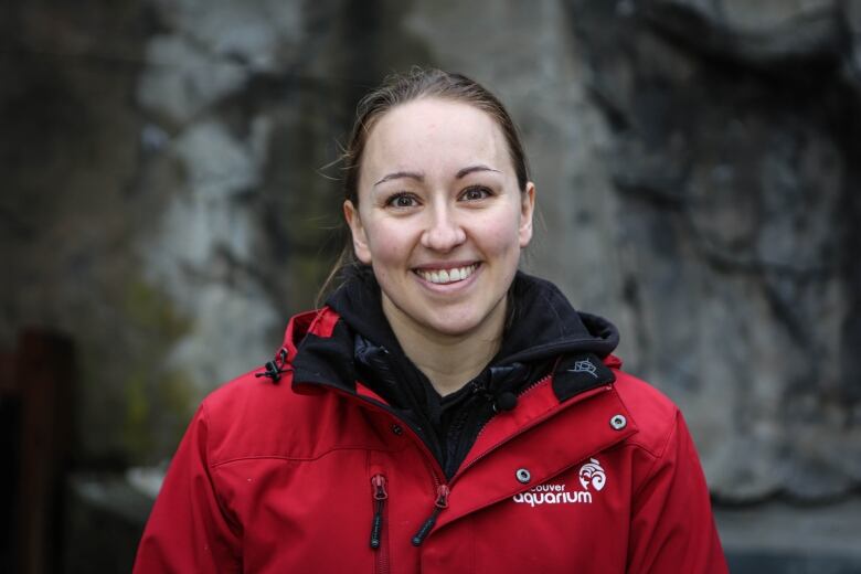 A woman wearing a red 'Vancouver Aquarium' jacket smiles at the camera 