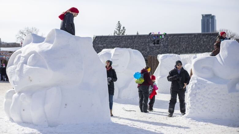 People play around giant snow sculptures.