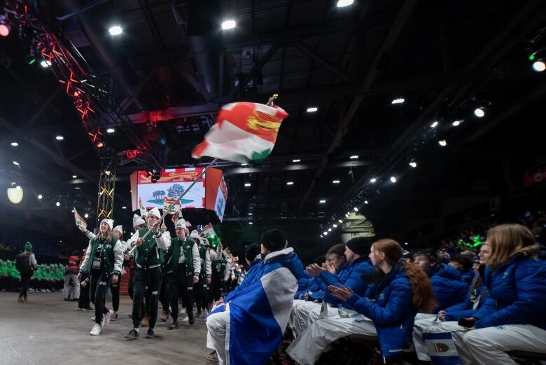 Athletes in PEI uniforms walk in to the Opening Ceremony waving the PEI flag 