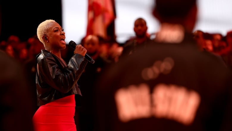 A woman in a red dress sings into a microphone