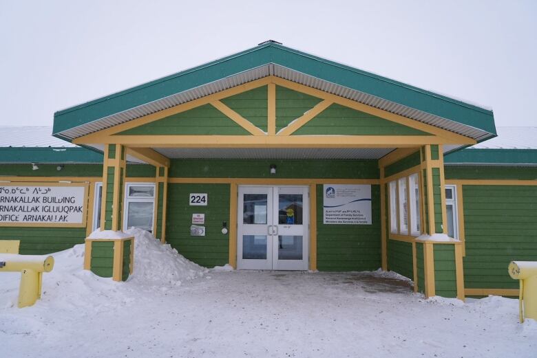 A squat, green and yellow office building sits in the snow.