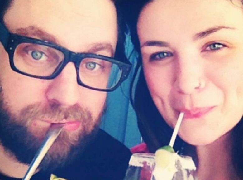 A couple takes a selfie while sipping drinks.