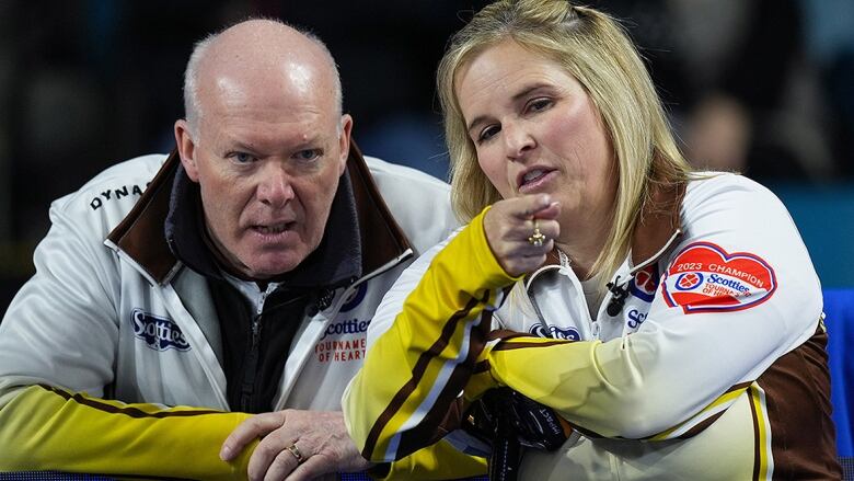 Men's curling coach and female player discuss strategy during match at Scotties Tournament of Hearts.