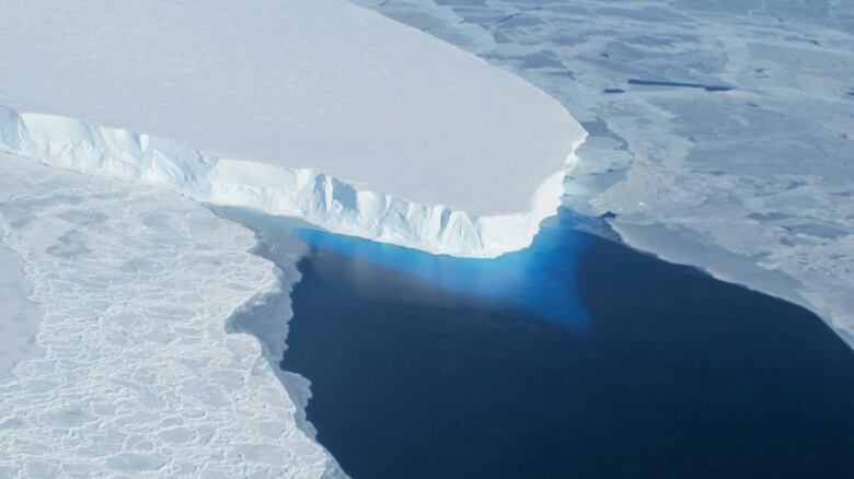 A large glacier sits in a blue sea.