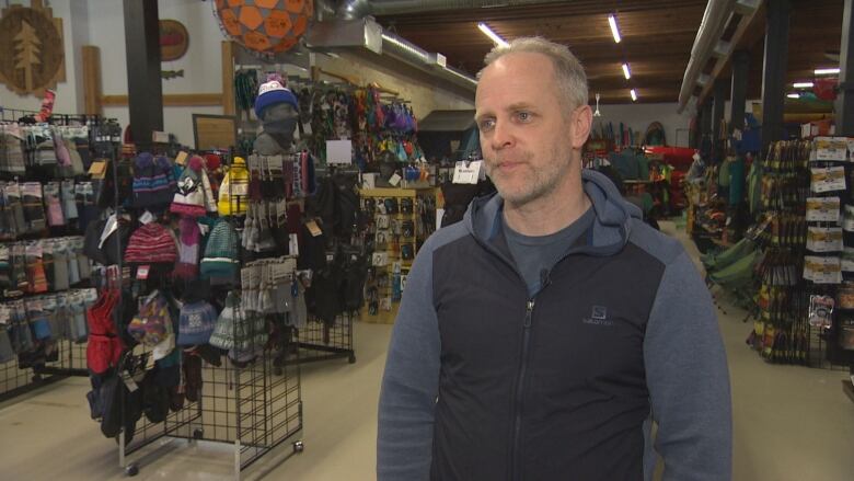 A man stands in a store filled with outdoor gear.