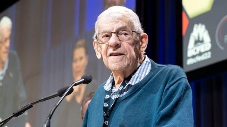 An older white man speaks at a podium