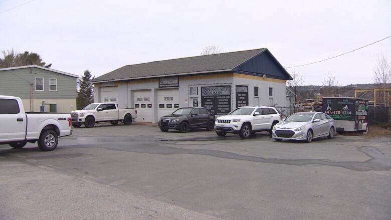 Several cars are parked outside a service centre, with a house visible next door.