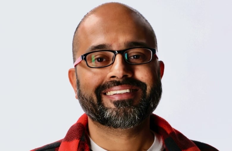 Close up headshot of Abhilash Kantamneni, who is smiling in front of a plain background. 